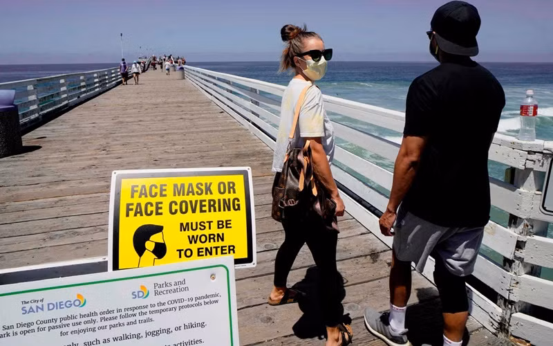 Du khách đến bãi biển tại San Diego, California bắt buộc phải đeo khẩu trang. (Ảnh: Getty Images)