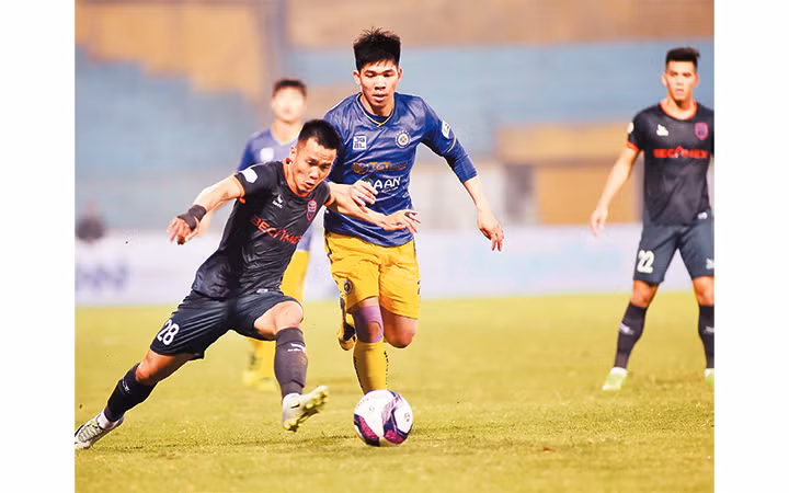 Pha tranh bóng giữa cầu thủ đội Hà Nội FC (áo tím) và cầu thủ đội Becamex Bình Dương. Ảnh: ĐỨC ANH