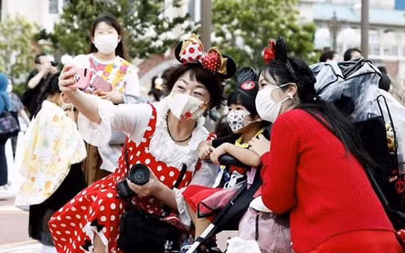 Du khách tới Công viên giải trí Disneyland Tokyo phải đeo khẩu trang bắt buộc (Ảnh: CNN)