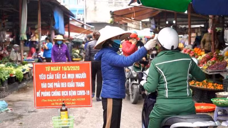 Kiểm tra thân nhiệt cho người dân tại chợ trung tâm TP Cẩm Phả (Quảng Ninh).
