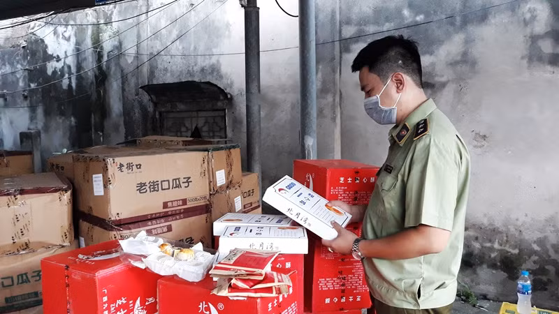 Cán bộ quản lý thị trường kiểm tra chất lượng sản phẩm bánh, kẹo nhập khẩu. (Ảnh: NGUYÊN TRANG)
