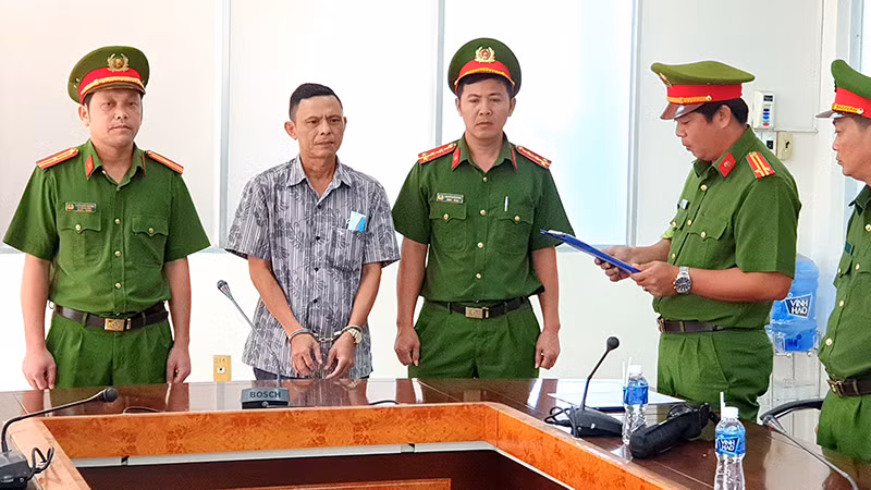 Cơ quan Cảnh sát điều tra Công an tỉnh Bình Thuận đọc Quyết định khởi tố bị can, Lệnh bắt tạm giam đối với Trần Văn Đông (áo sơ mi) tại nơi làm việc.