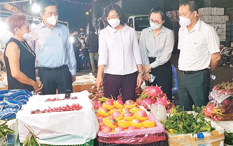 Lực lượng chức năng kiểm tra hoạt động kinh doanh của một gian hàng buôn bán trái cây tại chợ đầu mối nông sản-thực phẩm Thủ Đức. 
