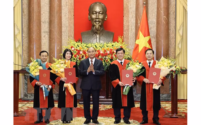 Chủ tịch nước Nguyễn Xuân Phúc trao quyết định và tặng hoa chúc mừng 4 thẩm phán Tòa án Nhân dân tối cao. (Ảnh: TTXVN) 
