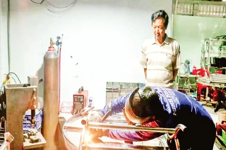 Ông Nguyễn Văn Kiệt quan sát thợ hàn thực hiện công đoạn hoàn thiện sản phẩm.