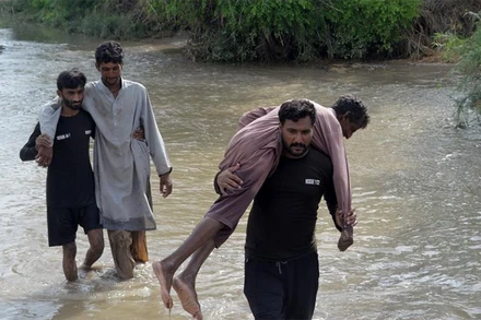 Người dân di chuyển qua đoạn đường bị ngập do mưa lũ tại Pakistan. (Ảnh: Tân Hoa Xã)