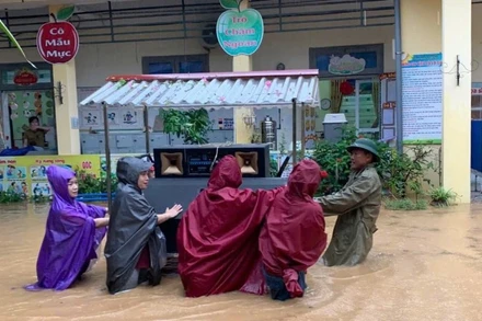 Giáo viên và lực lượng tại chỗ di chuyển đồ dùng học tập ra khỏi vùng ngập tại trường Tiểu học Sông Cầu. (Ảnh: KHÁNH LINH)