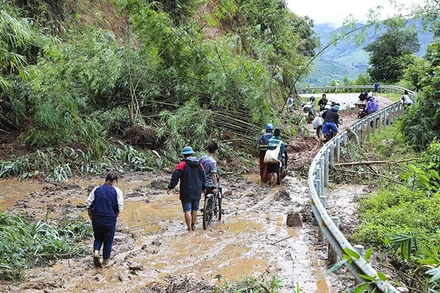Người và xe máy vất vả di chuyển qua các điểm sạt lở tại Điện Biên. (Ảnh: TTXVN) 