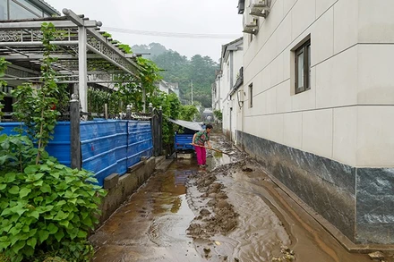 Người dân dọn bùn đất sau mưa lũ tại quận Mật Vân, Bắc Kinh, Trung Quốc. (Ảnh: THX/TTXVN)