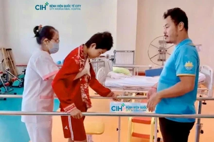 Bệnh nhi Toun Sreynich tập hồi phục với sự hỗ trợ của bác sĩ. 