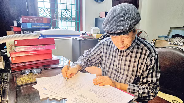 Nhà văn Minh Chuyên miệt mài bên trang bản thảo. (Ảnh: HẢI NAM)