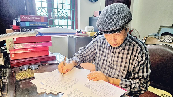 Nhà văn Minh Chuyên miệt mài bên trang bản thảo. (Ảnh: HẢI NAM)