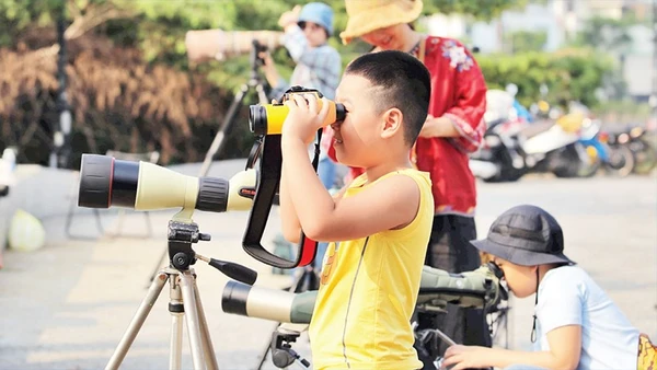 Các em nhỏ trải nghiệm ống nhòm chuyên dụng. 