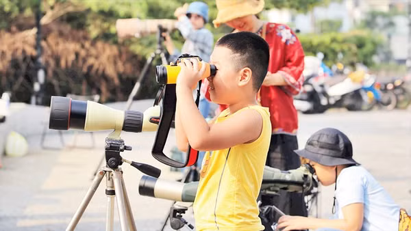 Các em nhỏ trải nghiệm ống nhòm chuyên dụng. 