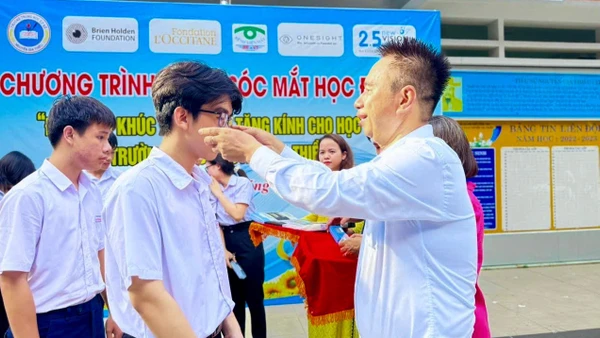 Bác sĩ Nguyễn Viết Giáp mang kính cho học sinh bị tật khúc xạ.