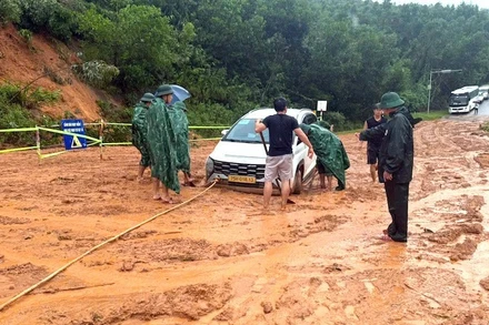 Các lực lượng chức năng tiến hành cứu hộ xe ô-tô bị mặc kẹt tại khu vực bị sạt lở.