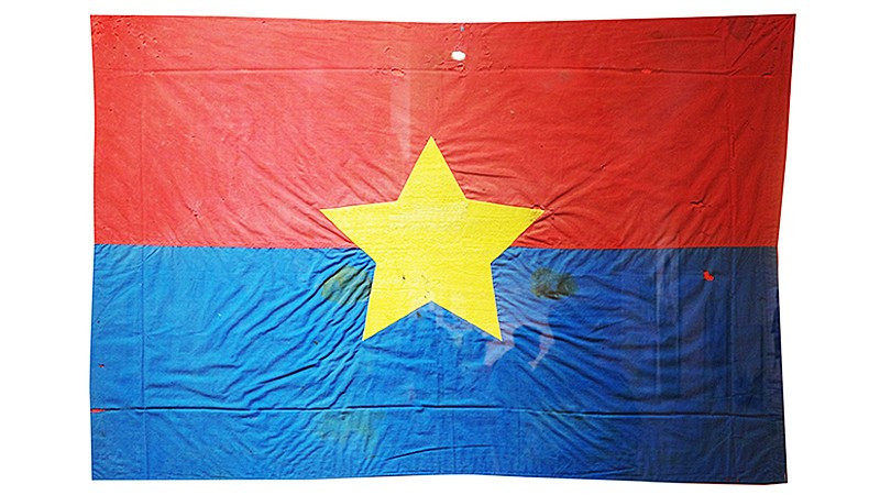 Cờ Mặt trận do nữ tù chính trị Côn Đảo may và thêu khi hay tin Hiệp định Paris ký kết. Lá cờ thấm máu tù chính trị được treo trước cửa dinh chúa đảo đúng ngày 1/5/1975.