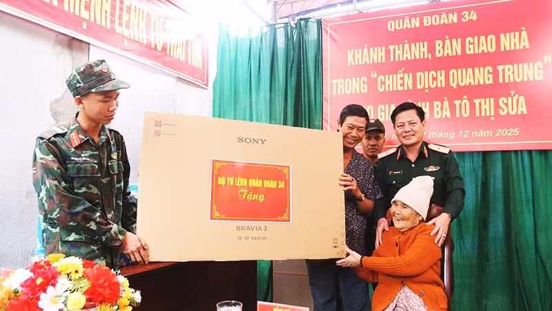 Bà Tô Thị Sửa vui mừng nhận quà của Quân đoàn 34 trong ngôi nhà mới.