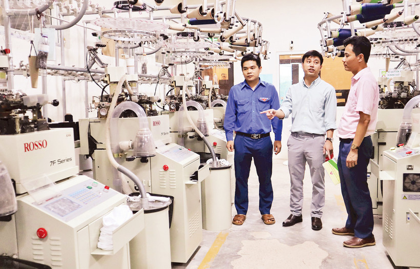 Anh Nguyễn Thanh Bình (đứng giữa), Giám đốc Công ty TNHH Begen, giới thiệu về dây chuyền sản xuất bít-tất xuất khẩu.