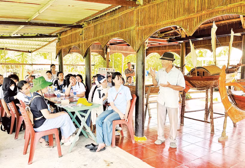 Du khách lắng nghe kể chuyện giữ gìn nghề đóng ghe bầu tại Làng mộc Kim Bồng.