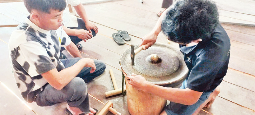 Các học viên thực hành chỉnh âm cồng chiêng tại lớp tập huấn do nhà nghiên cứu Bùi Trọng Hiền hướng dẫn. 