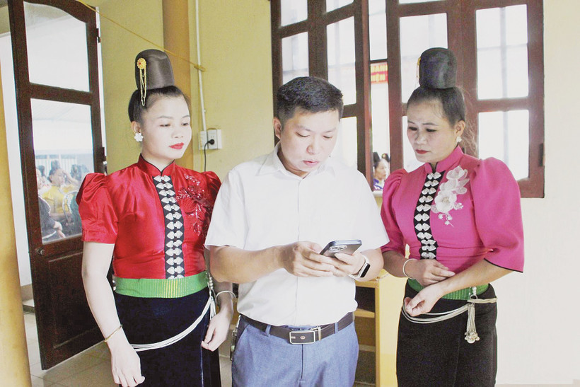 Cán bộ phường Chiềng Cơi hướng dẫn người dân cài đặt và sử dụng ứng dụng số trên điện thoại. Ảnh: BSL