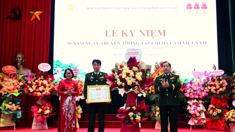 Trung tướng Nguyễn Hữu Chính tặng hoa chúc mừng và trao Bằng khen của Trung ương Hội Nạn nhân chất độc da cam/dioxin Việt Nam cho Tạp chí Da cam Việt Nam. 