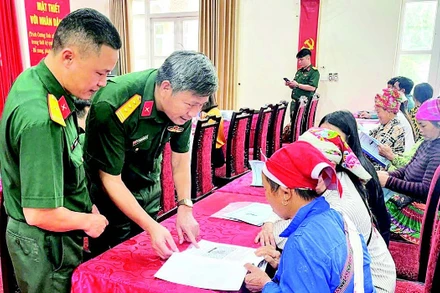 Cán bộ Đoàn Kinh tế-Quốc phòng 345 trao đổi, hướng dẫn người dân kỹ thuật chăn nuôi. (Ảnh QUANG PHẤN)