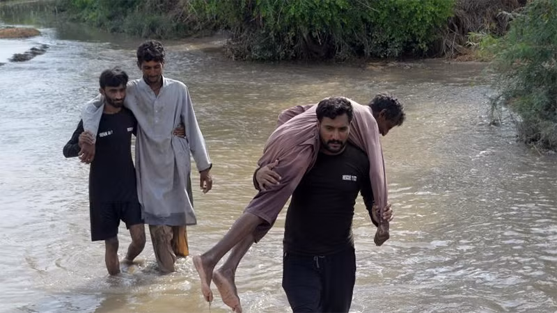 Người dân di chuyển qua đoạn đường bị ngập do mưa lũ tại Pakistan. (Ảnh: Tân Hoa Xã)