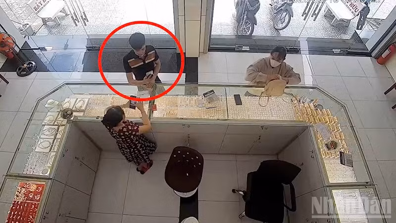 Đối tượng Sang đang thực hiện giao dịch chuyển tiền qua App giả tại cửa hàng kinh doanh vàng (khoanh đỏ).
