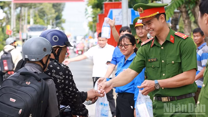 Cán bộ, chiến sĩ công an phát nước suối và khăn lạnh cho người dân về quê nghỉ lễ.