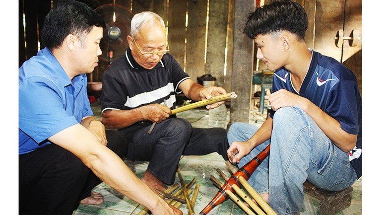 Già Hoàng Minh Tân (ngồi giữa) dạy thanh niên trẻ làm khèn. Ảnh: TÙNG VÂN 51.jpg