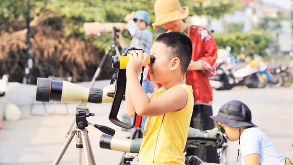 Các em nhỏ trải nghiệm ống nhòm chuyên dụng.