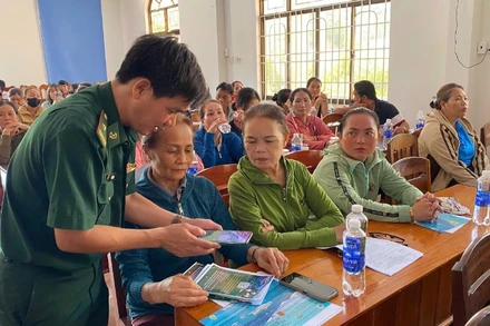 Cán bộ Đồn Biên phòng Tam Quan Nam phát tờ rơi tuyên truyền và hướng dẫn ngư dân quét mã QR.