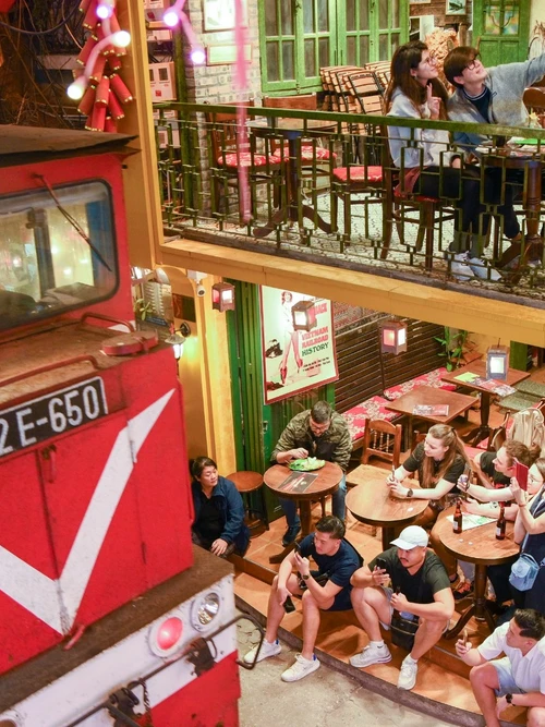 Khách du lịch ngồi sát khu vực đường ray khi tàu đi qua.