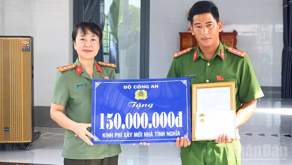 Đại tá Võ Thị Hoài Ngọc, Phó Giám đốc Công an tỉnh Đồng Tháp trao bảng tượng trưng kinh phí xây mới nhà tình nghĩa do Bộ Công an hỗ trợ tặng Đại úy Trần Minh Giàu. (Ảnh: PHƯỚC THANH)