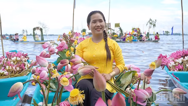 Duyên dáng bên chiếc xuồng sen trên cánh đồng mùa nước nổi. (Ảnh: HỮU NGHĨA)