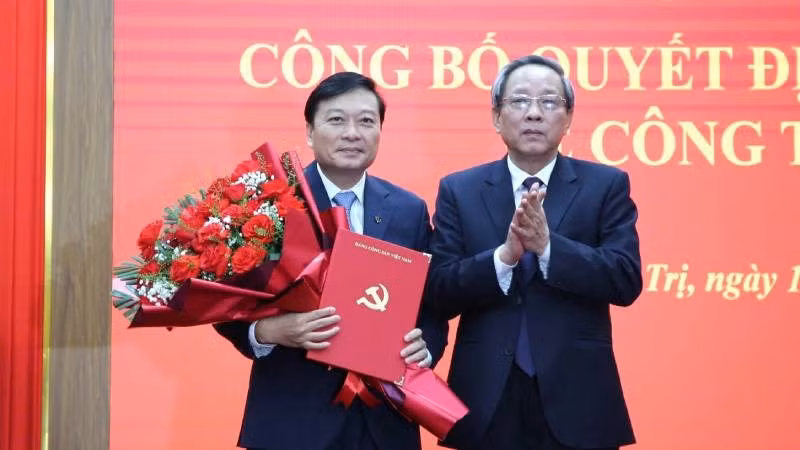 Đồng chí Hoàng Đăng Quang, Phó Trưởng Ban Thường trực Ban Tổ chức Trung ương trao quyết định và tặng hoa đồng chí Lê Hồng Vinh.