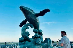 Du khách nước ngoài bên tượng Cá Ông