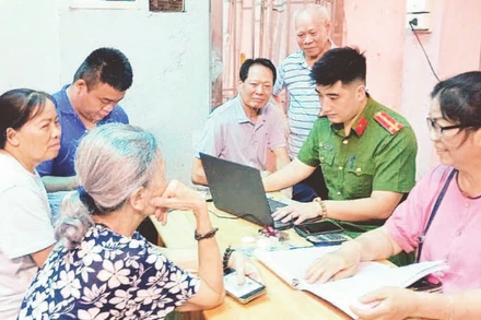 Công an phường Tây Hồ hướng dẫn cán bộ, đảng viên cài đặt ứng dụng thực hiện thủ tục hành chính đảng. (Ảnh QUANG THÁI)