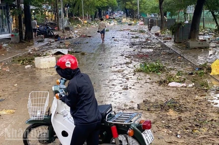 Người dân quay đầu xe trước con đường ngập rác thải sau lụt.