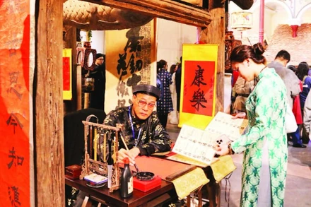 Du khách thích thú với hình ảnh ông đồ bên mực tàu, giấy đỏ trong phố cổ.