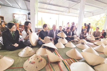 Du khách tìm hiểu các công đoạn chế tác nón ngựa tại cơ sở của Nghệ nhân Ưu tú Đỗ Văn Lan.