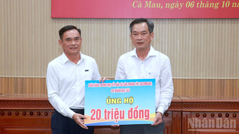 Đại diện một tổ chức ngân hàng có chi nhánh tại Cà Mau trao bảng tượng trưng quyên góp ủng hộ đồng bào vùng thiên tai. ndo_br_ung-ho-3-9954.jpg