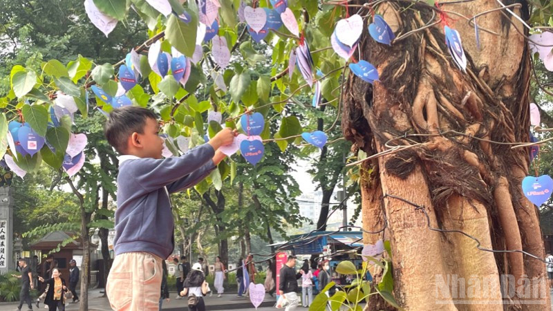 Em bé gửi gắm điều ước lên Cây Hạnh phúc. 