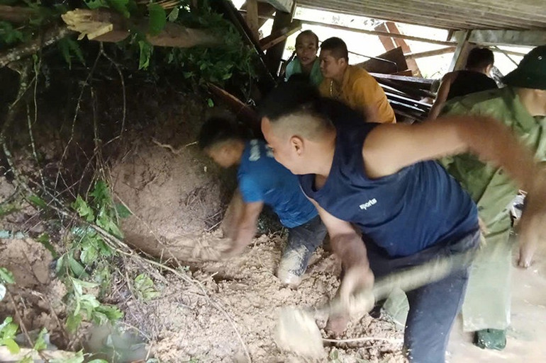 Lực lượng chức năng khẩn trương xử lý đất đá sạt lở, đè chặn ngôi nhà cùng đồng đội. 2.jpg