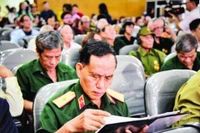 Thiếu tướng Trịnh Xuân Chuyền đọc những dòng chữ trong hồ sơ của đồng đội được trao trả. (Ảnh GIA KHÁNH)