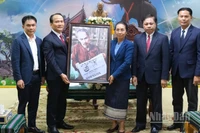 Phó Bí thư Thường trực Thành ủy Đà Nẵng Nguyễn Đình Vĩnh và đồng chí Phan Thái Sơn, quyền Trưởng đại diện Báo Nhân Dân tại miền trung-Tây Nguyên trao tặng bức ảnh Bác Hồ đọc Báo Nhân Dân cho lãnh đạo tỉnh Attapue-Lào. (Ảnh: ANH ĐÀO)