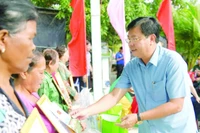 Bí thư Tỉnh ủy An Giang Nguyễn Tiến Hải trao quà tặng người dân tại lễ bàn giao nhà đại đoàn kết trong chương trình “Xóa nhà tạm, nhà dột nát”. (Ảnh QUỐC TRINH)
