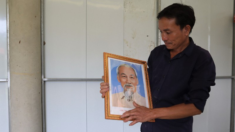 Anh đang ngắm nghía, tìm vị trí trang trọng để treo di ảnh Bác Hồ trong ngày đầu chuyển vào ngôi nhà mới. img-8003-3-5677.jpg